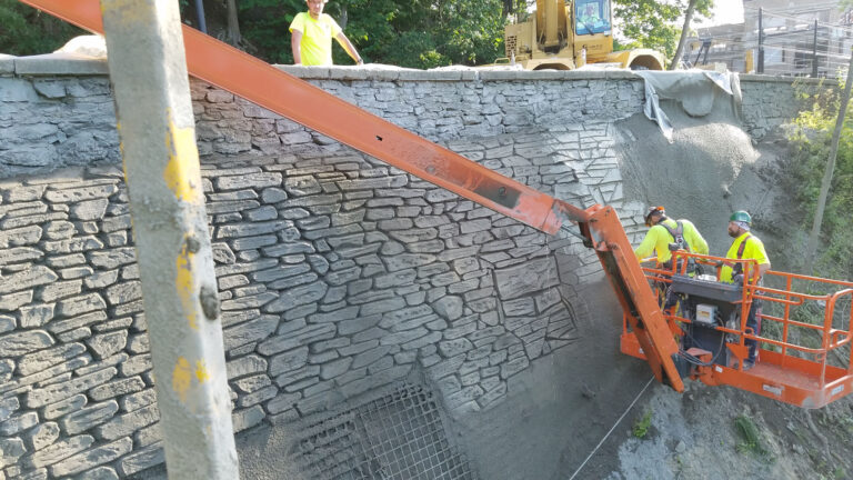 Workers hand sculpting shot-crete facing for retaining wall repair